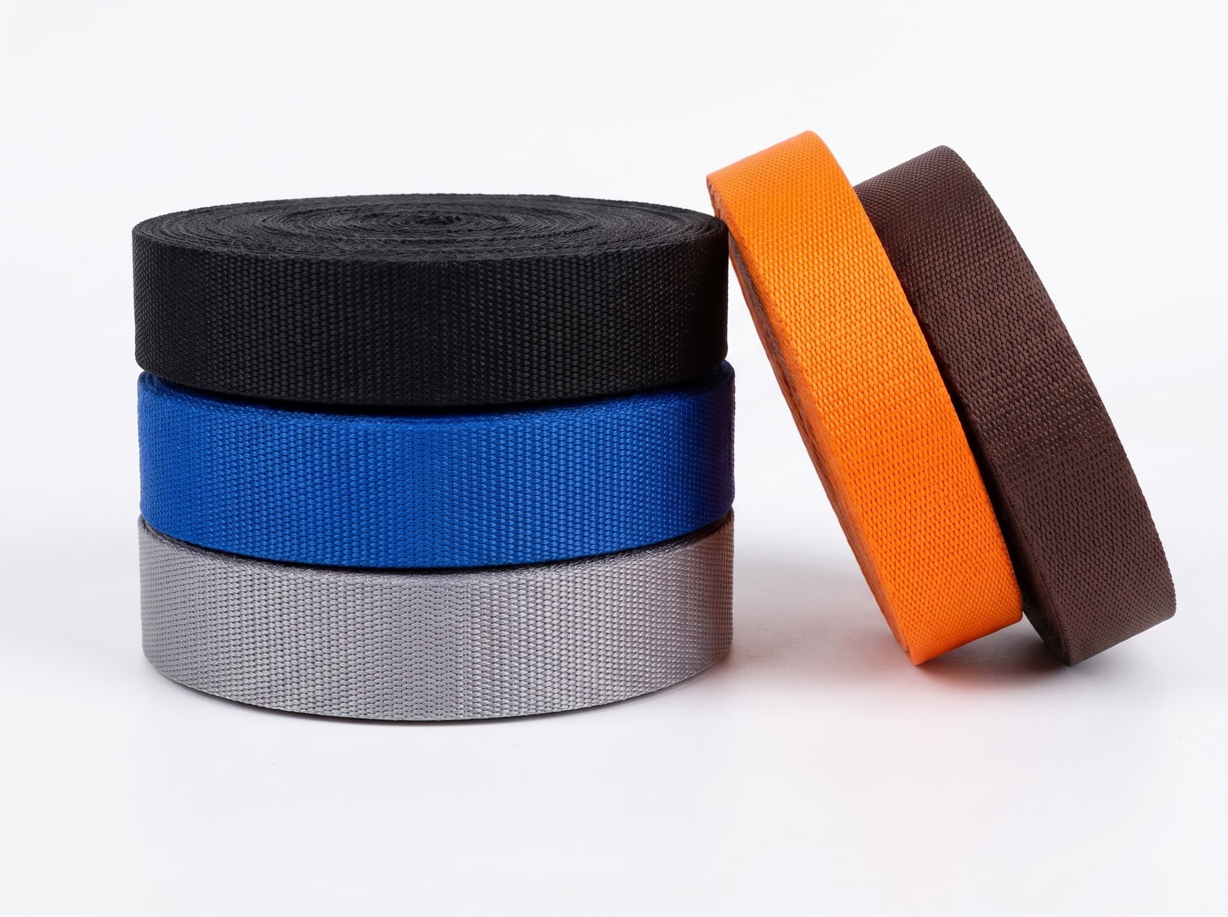Black, blue, silver, orange, and brown polypropylene webbing rolls on a white studio background